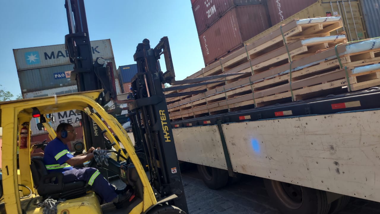 Operador de empilhadeira carregando pallets de madeira em carreta no pátio de contêineres